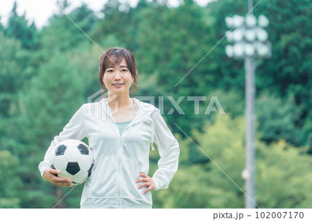 運動場でサッカーボールを持つサッカーファン・サポーターの日本人女性 102007170