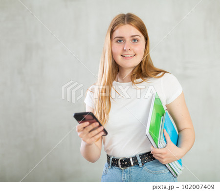 Portrait of female student with a mobile phone in her hand 102007409