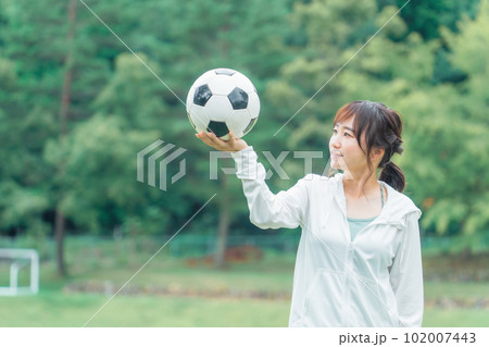 運動場でサッカーボールを見るサッカーファン・サポーターの日本人女性 102007443