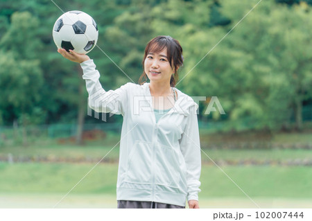 運動場でサッカーボールを持つサッカーファン・サポーターの日本人女性 102007444