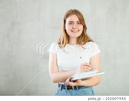 Positive girl student makes notes in notebook. Education in high school university college concept 102007448