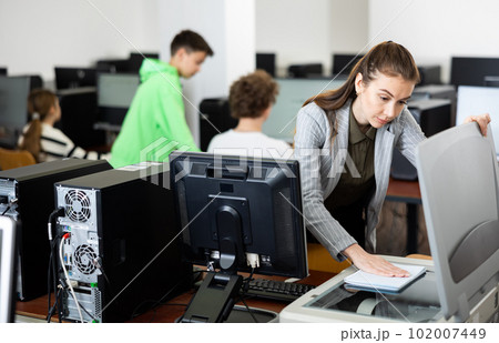 Woman copying notes on copy machine in library computer lab 102007449