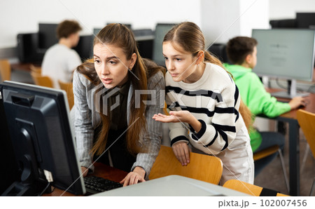Female teacher consulting teenage girl studying in information technology class 102007456