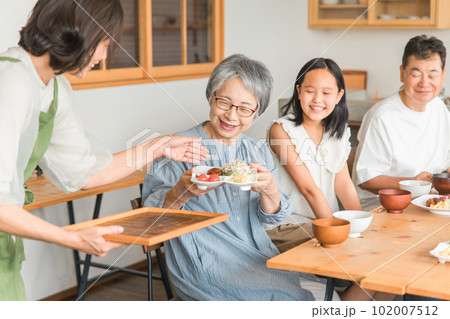 家のダイニングで家族団欒して食事する子供と夫婦・親子・三世代家族（二世帯住宅） 102007512