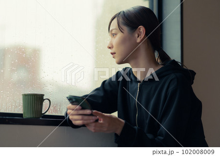 窓辺でスマホを手にコーヒーを飲む物憂げな顔をした若い女性 窓辺でスマホを手にコーヒーを飲む物憂げな顔をした若い女性 102008009