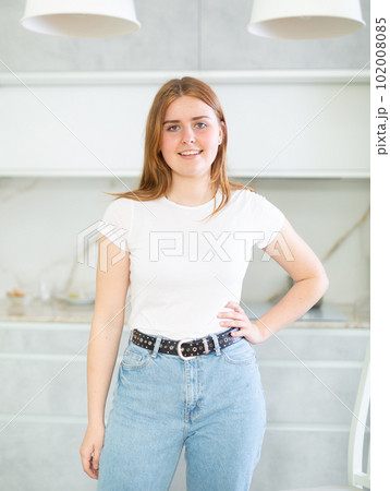 Portrait of cheerful European teen girl smiling at camera while posing in cozy kitchen Portrait of cheerful European teen girl smiling at camera while posing in cozy kitchen 102008085