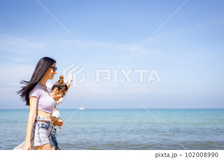 Happy female couple or bisexual couple enjoy walking along the beach together, women holding a hands together and running along the beach. LGBTQ people concept. Happy female couple or bisexual couple enjoy walking along the beach together, women holding a hands together and running along the beach. LGBTQ people concept. 102008990