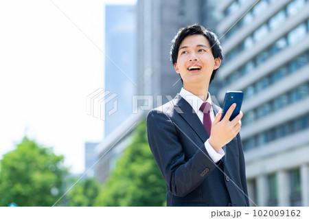 新入社員の男性ビジネスマンがスマホを使ってオフィス街で仕事をする 新入社員の男性ビジネスマンがスマホを使ってオフィス街で仕事をする 102009162