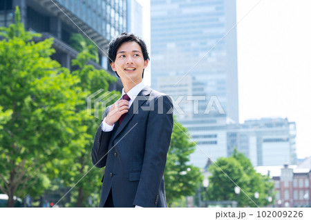 スーツ姿の新入社員の男性のビジネスマンがオフィス街で仕事をする スーツ姿の新入社員の男性のビジネスマンがオフィス街で仕事をする 102009226