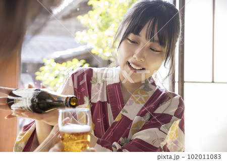 旅館食事イメージ　女子旅　友達にビールを注ぐ若い女性 102011083