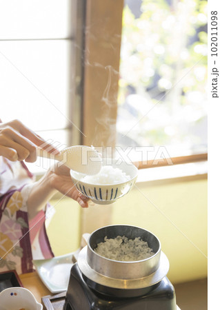 旅館朝食イメージ　お釜で炊いた炊き立てご飯をよそる女性手元 102011098