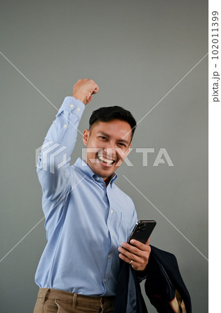 Overjoyed Asian businessman raising his hand, rejoicing, celebrating his success Overjoyed Asian businessman raising his hand, rejoicing, celebrating his success 102011399
