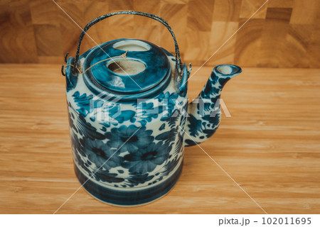 Old Chinese porcelain teapot, with green tea on the wooden. 102011695