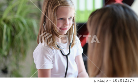 Cute little girl checks organs of woman with stethoscope 102012277