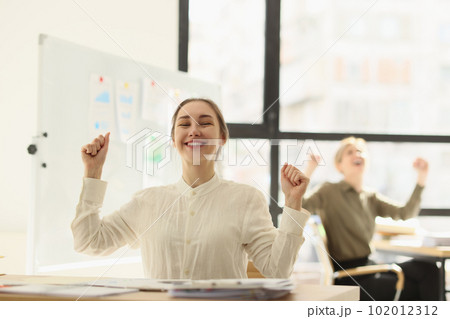Happy woman smiles raising hands at end of working day Happy woman smiles raising hands at end of working day 102012312
