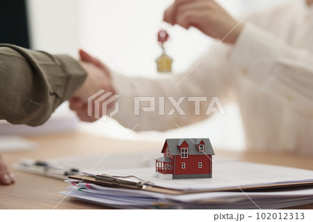 Female real estate agent gives key to house to client Female real estate agent gives key to house to client 102012313