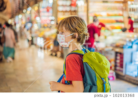 Boy tourist walks among the countless shops at the Grand Bazaar and Egyptian Bazaar in Istanbul. Shopping and travel in Turkey concept. Istanbul historical Egyptian Bazaar. Misir Carsisi, spice market 102013368