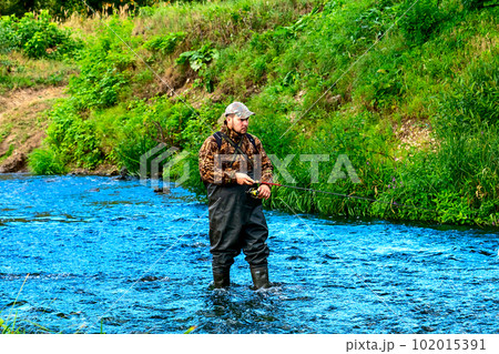 A fisherman catches fish while standing in the water A fisherman catches fish while standing in the water 102015391