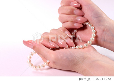 パールのネックレスを持つ女性の手 102017978
