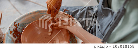 Young potter working on potter wheel in workroom 102018159