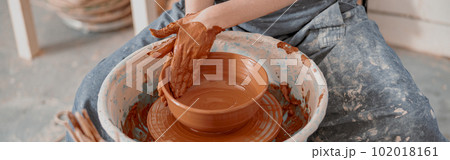 Young woman works on pottery wheel in atelier 102018161