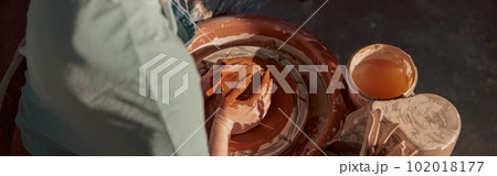 Young potter working on potter wheel in workroom Young potter working on potter wheel in workroom 102018177