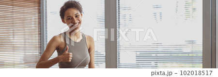 Afro american sporty woman sit on floor and preparing for online fitness class from home 102018517