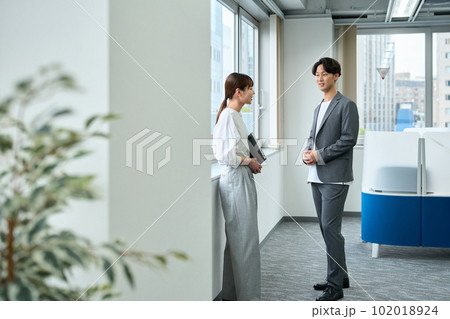 オフィスで立ち話をする男女 オフィスで立ち話をする男女 102018924