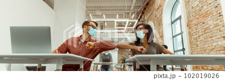 Students siting and greeting bumping elbows at workplace Students siting and greeting bumping elbows at workplace 102019026