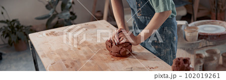 Handmade artist shaping clay while making ceramics in pottery workshop 102019261