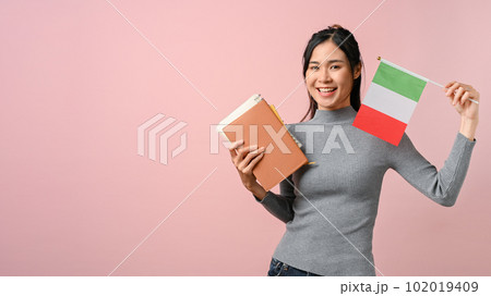 Beautiful young Asian woman showing a Italy flag on pink isolated background. 102019409
