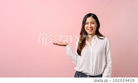 Young beautiful Asian woman spreading pointing hands aside on pink isolated background. 102019419