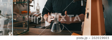 Men barista making a drip filter coffee standing by counter in coffeeshop 102019603