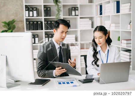 Two business workers talking on the smartphone and using laptop at the office. 102020797