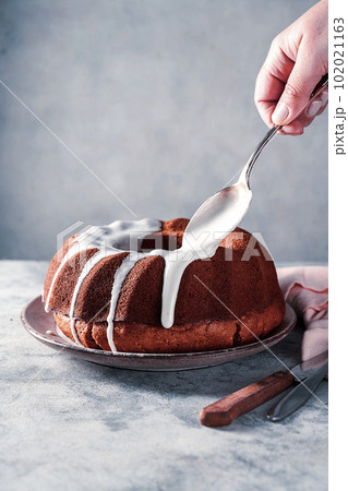 Bundt cake. Drizzling icing on homemade pound, cake.  102021163