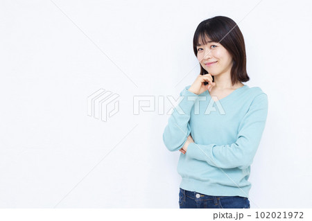 白い背景の前で笑顔で考えている30代の女性 102021972