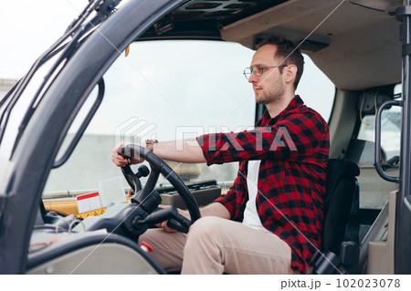 Young Rural Tractor or Combine driver sitting in the cab. Farming and harvesting Young Rural Tractor or Combine driver sitting in the cab. Farming and harvesting 102023078