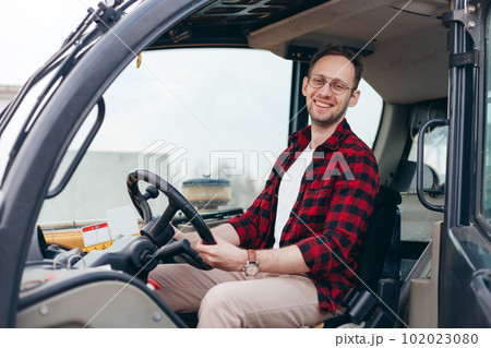 Young Rural Tractor or Combine driver sitting in the cab. Farming and harvesting 102023080