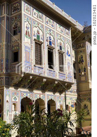 Colourful paintings and wooden windows on the outer wall of Seth Harmukhrai Sanehiram Chokhani Double Haveli, located in Mandawa, Shekhawati, Rajasthan, India Colourful paintings and wooden windows on the outer wall of Seth Harmukhrai Sanehiram Chokhani Double Haveli, located in Mandawa, Shekhawati, Rajasthan, India 102023481