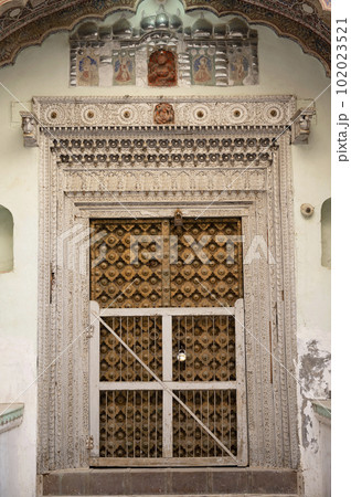 Colourful paintings on the inner wall and wooden door of 1100 Khidkiyon Ki Haveli, owned by Babulal Surana, located in Churu, Shekhawati, Rajasthan, India 102023521