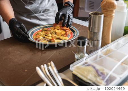 Close up of chef giving out finished dish at ordering station in open restaurant kitchen 102024469