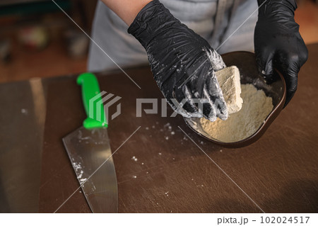 The chef breads the cheese in flour before frying it in a pan in restaurant kitchen The chef breads the cheese in flour before frying it in a pan in restaurant kitchen 102024517