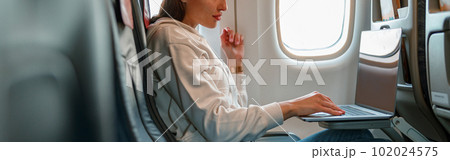 Female traveler using laptop in passenger airplane 102024575