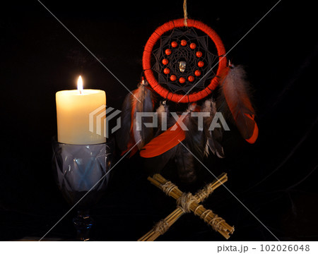 Esoteric and occult still life with vintage magic dreamcatcher and burning candle on witch table altar for mystic rituals and fortune telling. Halloween and gothic background Esoteric and occult still life with vintage magic dreamcatcher and burning candle on witch table altar for mystic rituals and fortune telling. Halloween and gothic background 102026048