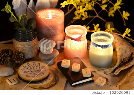 Esoteric and occult still life with vintage magic objects, runes and burning candles on witch table altar for mystic rituals and fortune telling. Halloween and gothic background 102026095