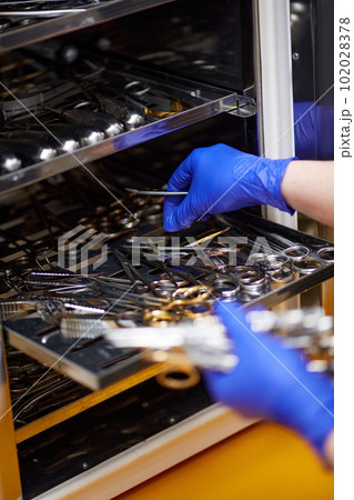 Doctor's hands, veterinarian picking up surgery and examining tools, instruments from steriliser at vet clinic. Disinfection 102028378