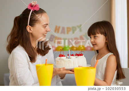 Portrait of mother and little girl celebrating birthday with delicious cake for her little daughter, waiting to blow the candles smiling, looking at each other with love and gentle. Portrait of mother and little girl celebrating birthday with delicious cake for her little daughter, waiting to blow the candles smiling, looking at each other with love and gentle. 102030553
