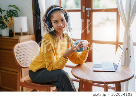 Portrait of an African American wearing headphones holding a coffee cup and using a computer. Portrait of an African American wearing headphones holding a coffee cup and using a computer. 102034102