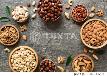 mixed nuts in wooden bowl. Mix of various nuts on colored background. pistachios, cashews, walnuts, hazelnuts, peanuts and brazil nuts 102034294