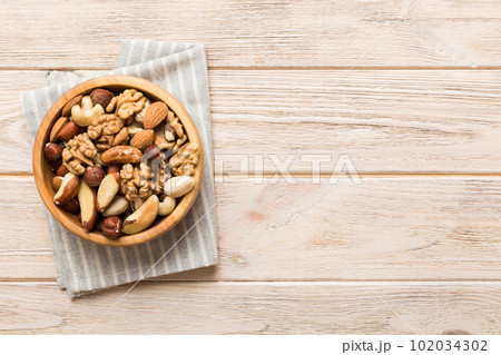 mixed nuts in bowl. Mix of various nuts on colored background. pistachios, cashews, walnuts, hazelnuts, peanuts and brazil nuts 102034302